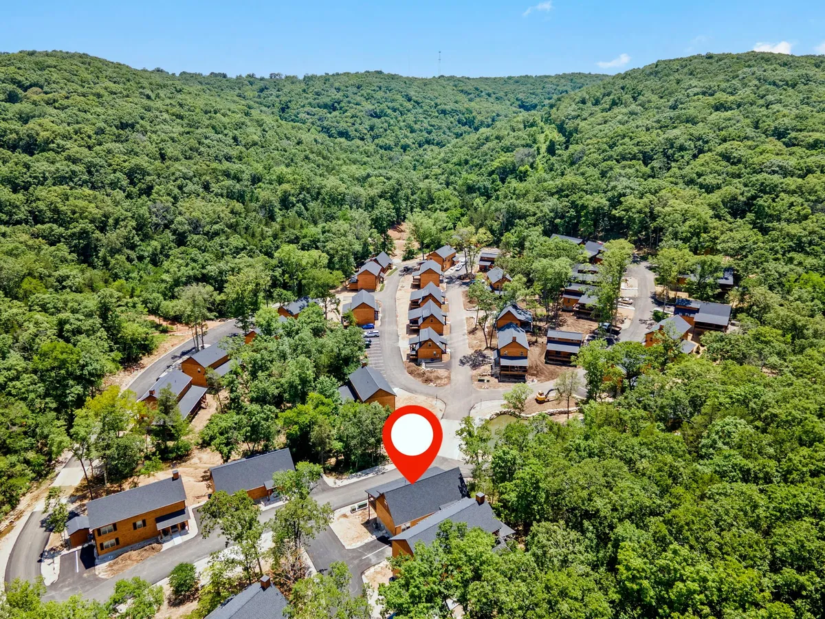 Rows of newly constructed wooden cabins line gently curved roadways, surrounded by dense greenery. The area feels open, tranquil, and ready to welcome its first guests, with a sense of community forming amidst nature.