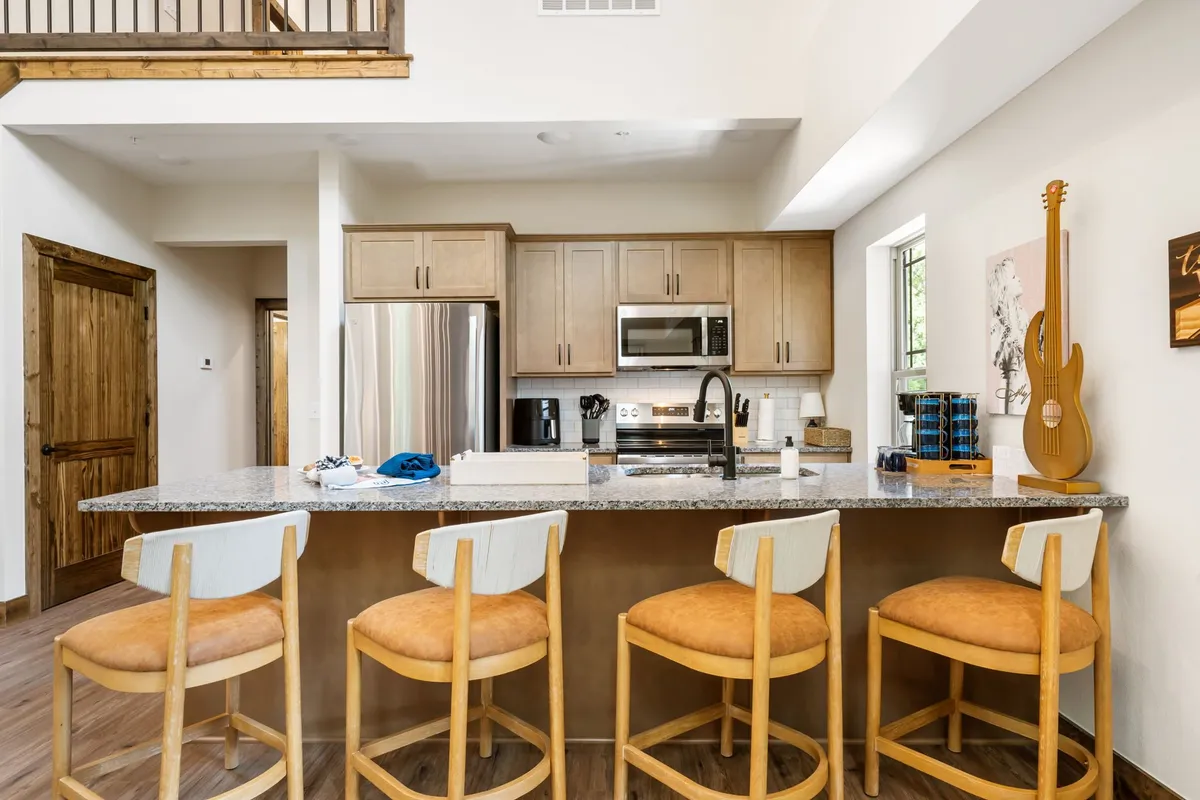 A welcoming kitchen space with a central island surrounded by bar stools, modern appliances, and a cozy atmosphere inviting both cooking and conversation. The island encourages social interaction during meal prep or casual breakfasts.