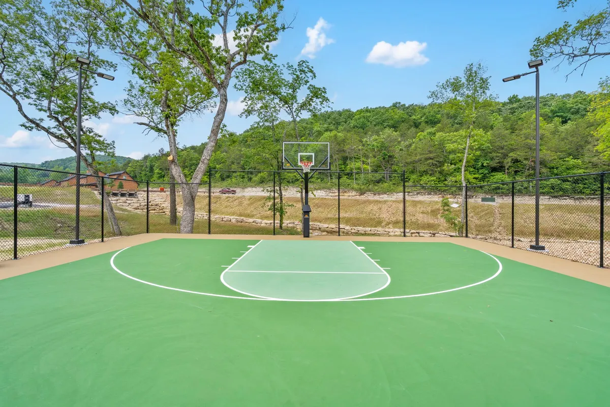 A basketball court nestled among trees and set against a mountain backdrop. The court looks ready for friendly games, with the open space inviting group activities and social gatherings outdoors.